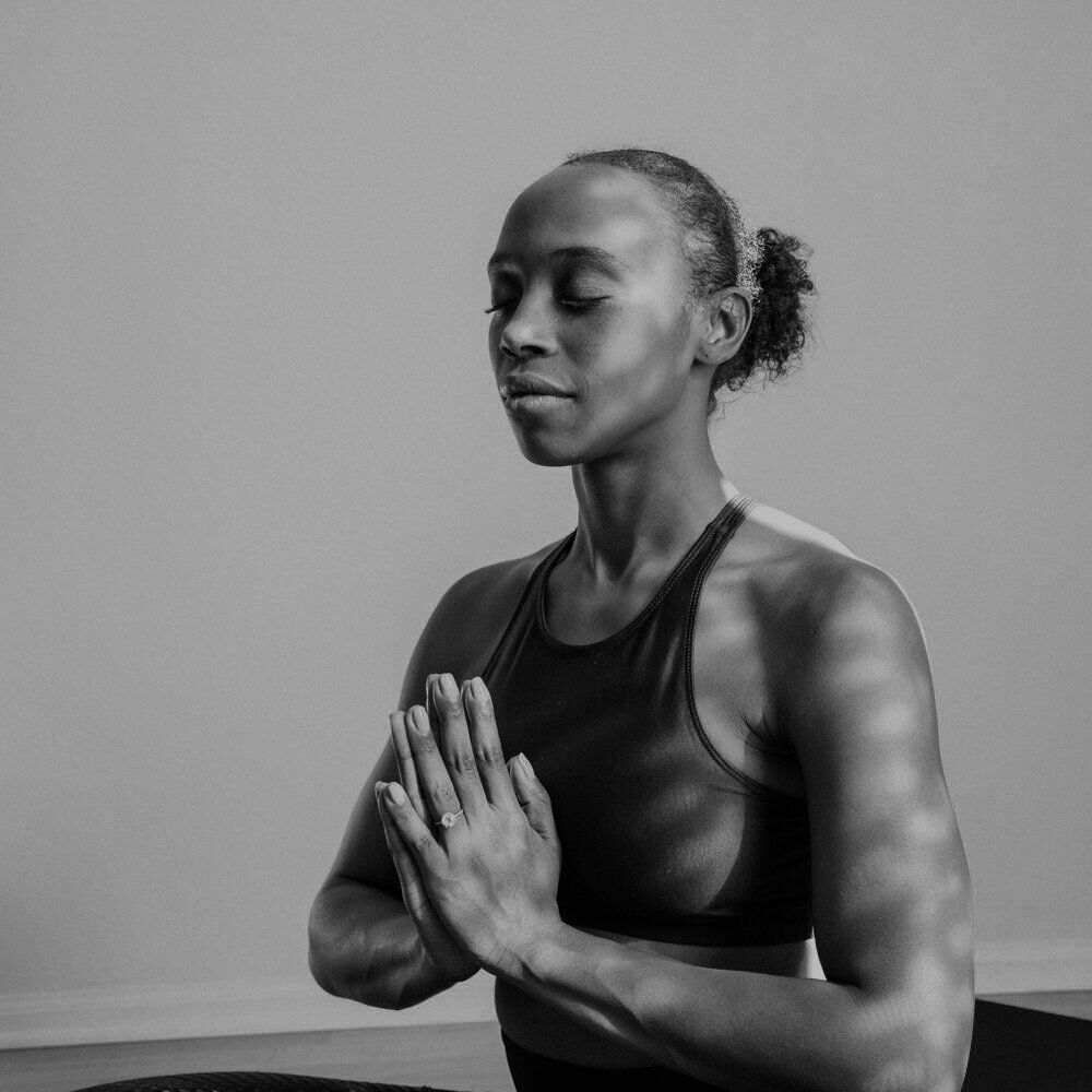 Black-and-white portrait of a woman with her eyes closed and her hands pressed together