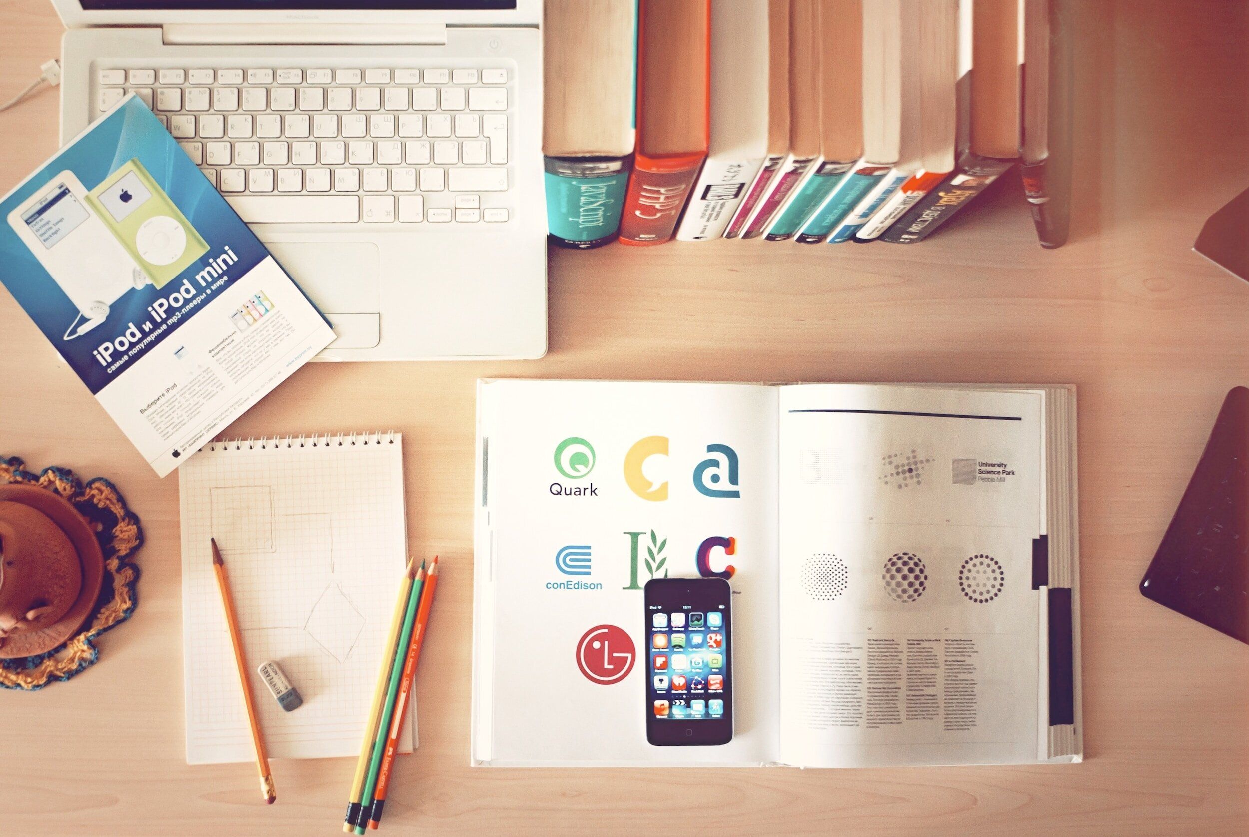 A designer’s desk with sketches, coloured pencils and a book of logo designs
